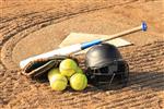 Softball bat, glove, helmet, and balls sitting atop home plate.